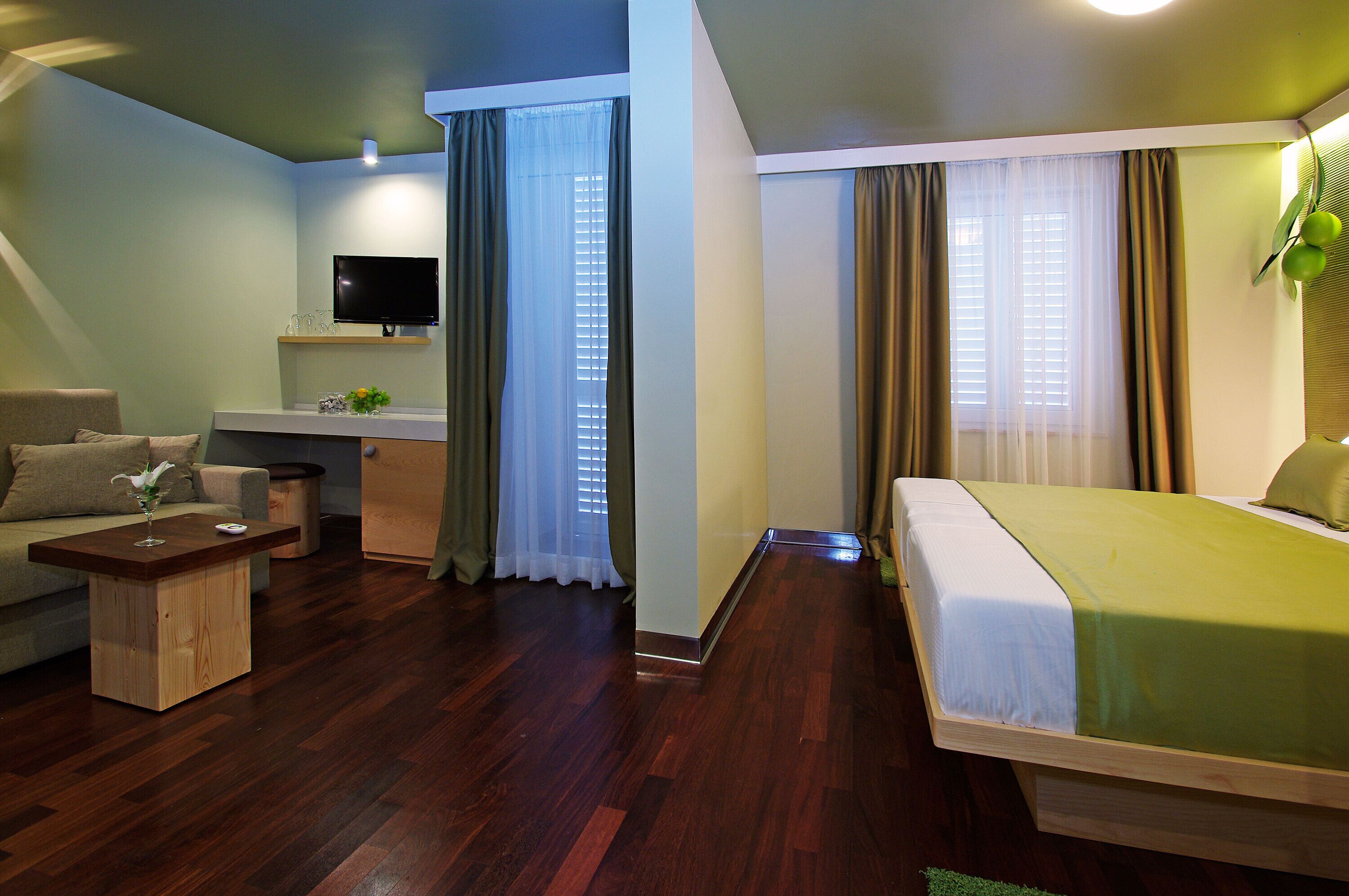 A hotel room with a bed, a sofa, a TV, and a desk.