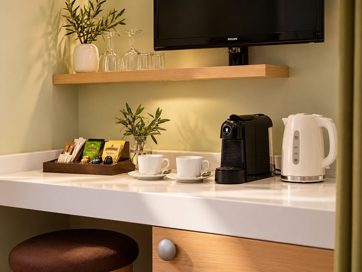 A kitchen counter with a coffee maker, a kettle, and a tray of tea bags.