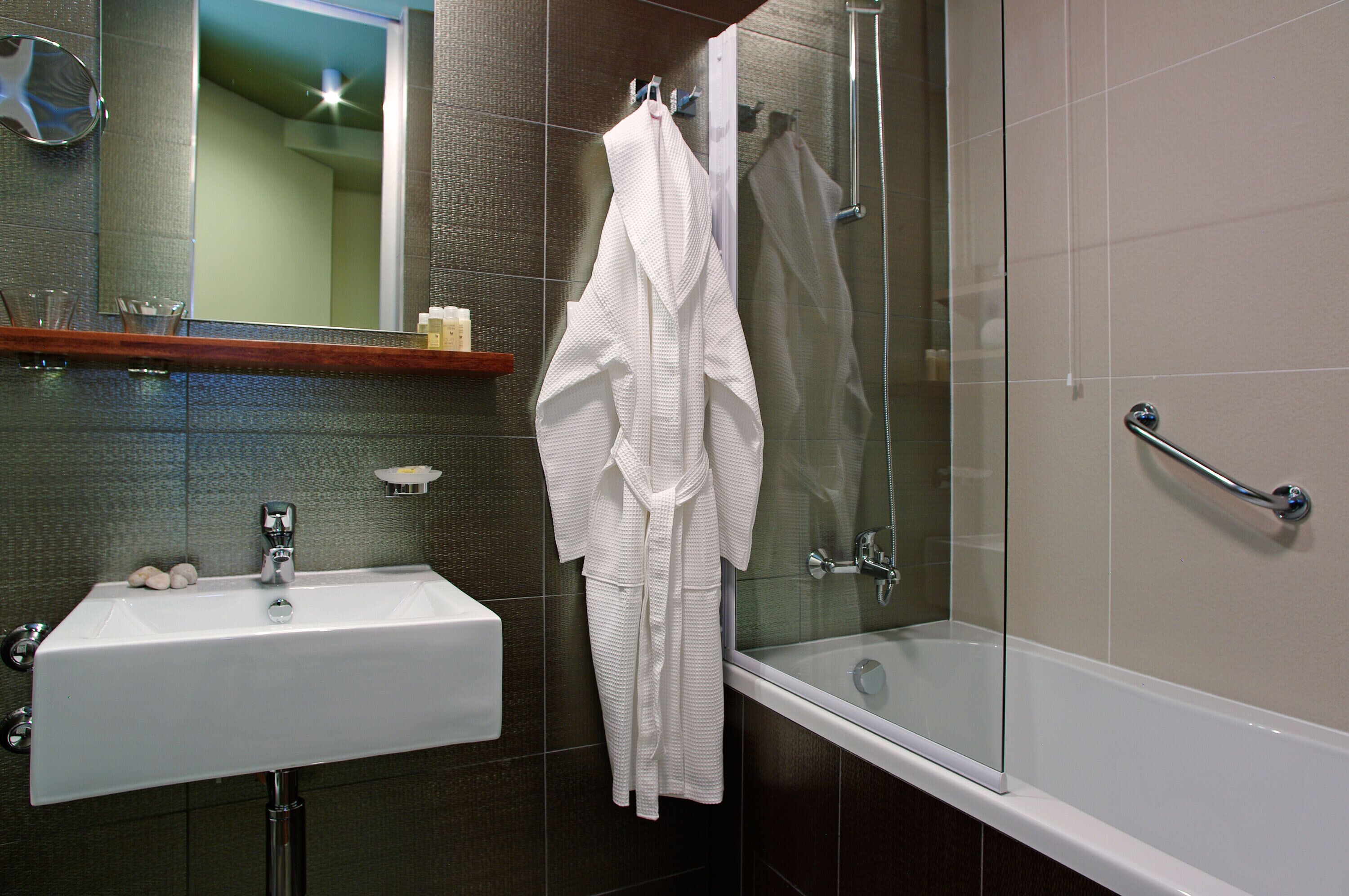 A bathroom with a white sink, glass shower enclosure, and a glass door.