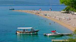 A beach with boats, a lifeguard tower, and beach umbrellas. - Boutique Hotel Bol (Bol)