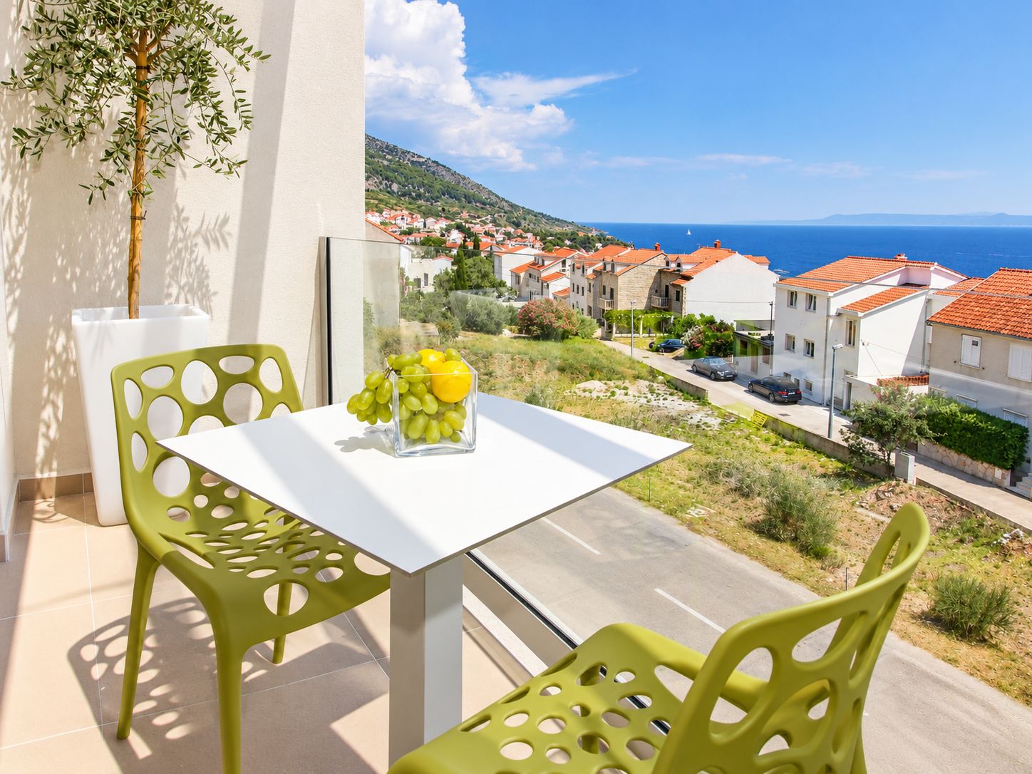 Un balcon avec une table, des chaises et un vase rempli de fruits.