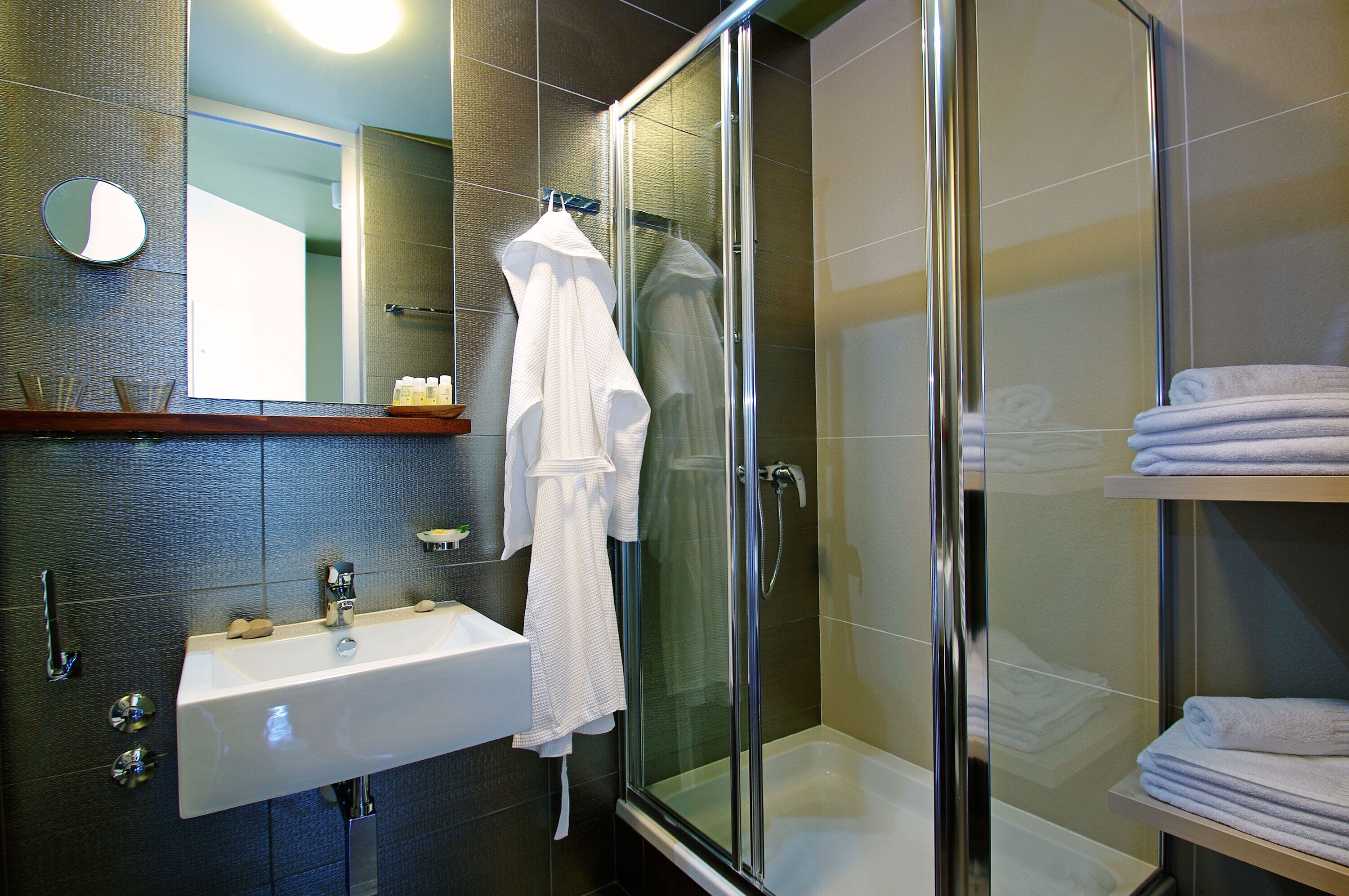 Un bagno moderno con doccia vetrata, lavandino bianco e specchio.