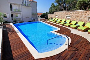 A swimming pool with lounge chairs and a stone wall. - Boutique Hotel Bol (Bol)