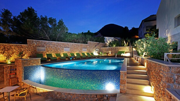 A swimming pool with a mosaic tile edge, surrounded by stone walls and a staircase leading up. - Boutique Hotel Bol (Bol)