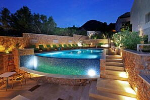 A swimming pool with a mosaic tile edge, surrounded by stone walls and a staircase leading up. - Boutique Hotel Bol (Bol)