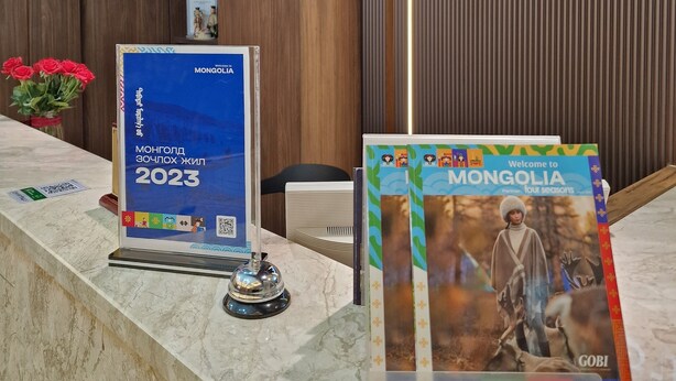 En receptionsdisk med en skylt som visar texten ”NEWWEST” och informationsbroschyrer om Mongoliet.