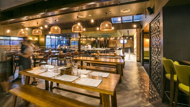 A spacious restaurant with multiple dining tables and benches, overhead lighting, and a high ceiling. - Nightcap at Caringbah Hotel (Caringbah)