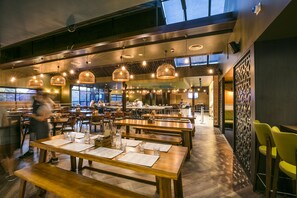 A spacious restaurant with multiple dining tables and benches, overhead lighting, and a high ceiling. - Nightcap at Caringbah Hotel (Caringbah)