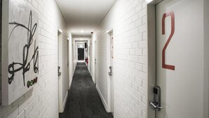 A hotel hallway with white brick walls, a dark carpet, and doors numbered 2 and 3. - Nightcap at Caringbah Hotel (Caringbah)
