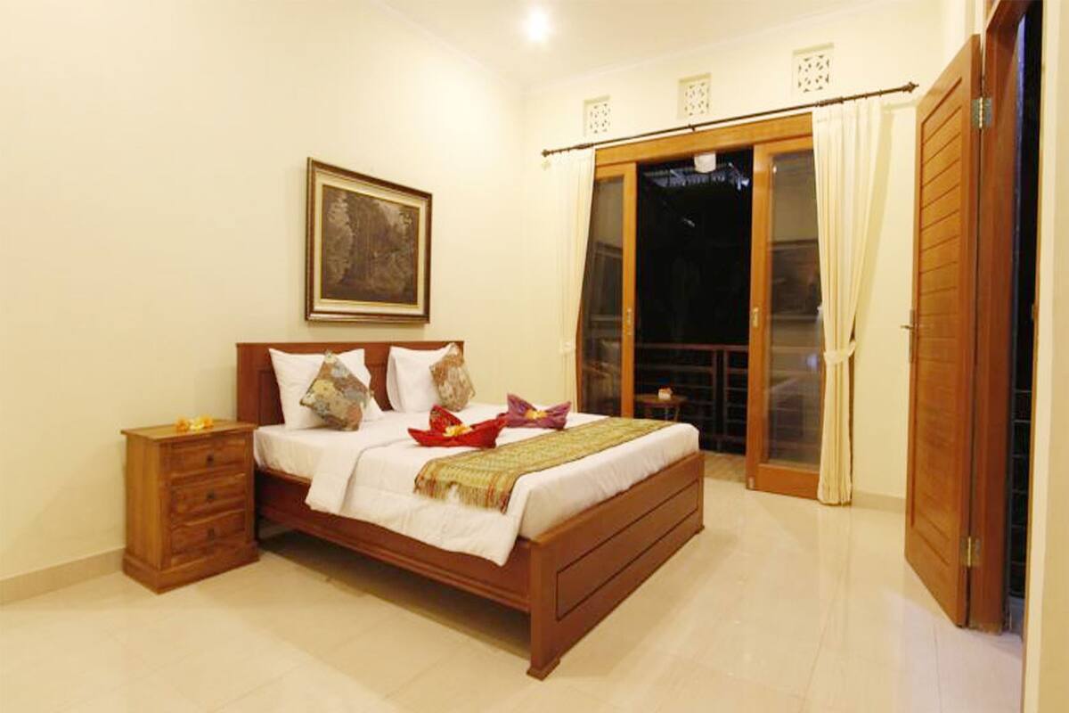Un dormitorio con cama de madera, una mesita de noche, un cuadro en la pared y una puerta corrediza al exterior.