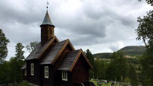 A wooden church with a bell tower, surrounded by a cemetery with gravestones. - Stor-Elvdal Hotell (Stor-Elvdal)