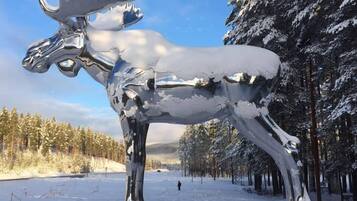 A large metallic moose sculpture in a snowy forest setting.
