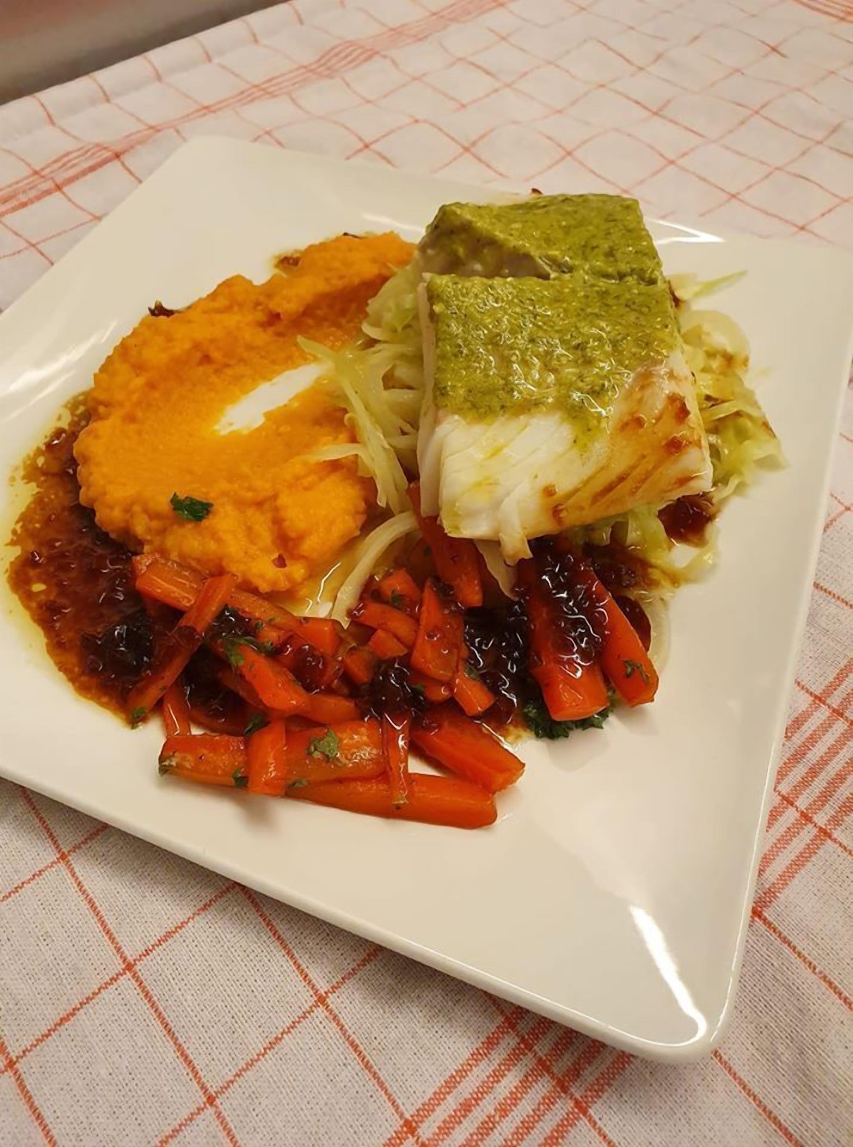 Ein Teller mit Fisch, Kartoffelstampf und gerösteten Karotten.