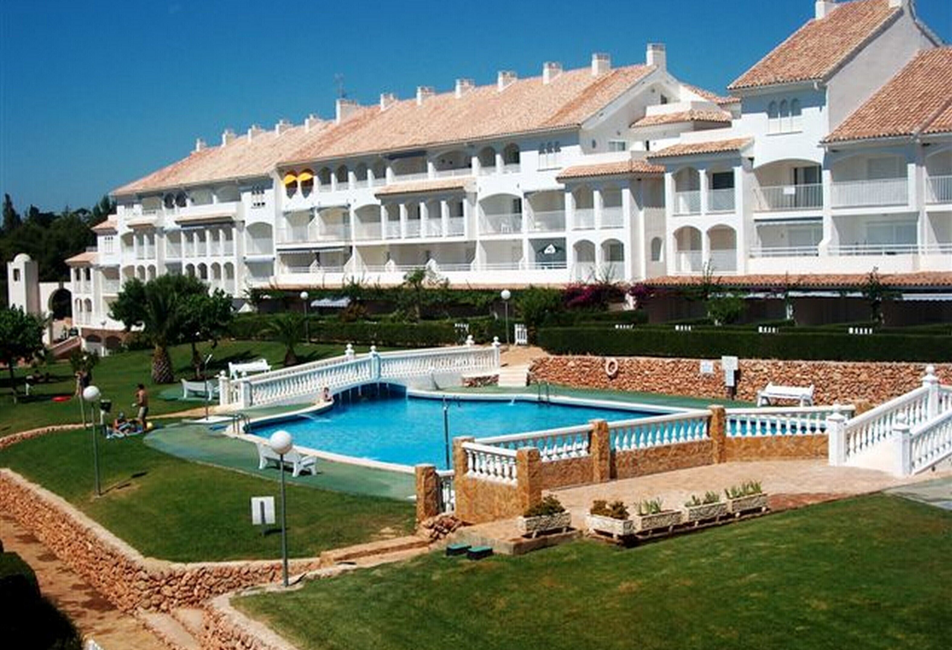 Un grand hôtel blanc doté de nombreux balcons et d’une piscine centrale.