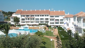 Un grand hôtel doté de nombreux balcons, d’une piscine et de jardins bien entretenus.