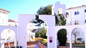 Un bâtiment blanc, doté d’arcades, avec un chemin de pierre menant à une cour intérieure.