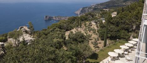 A coastal property with a patio area, outdoor seating, and a view of the sea and rocky coastline.