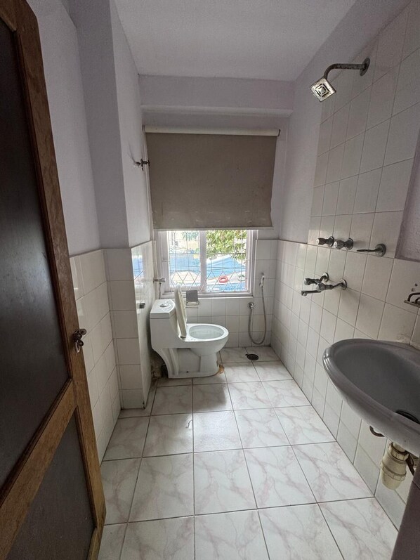 Un baño pequeño con inodoro, lavamanos y ducha.