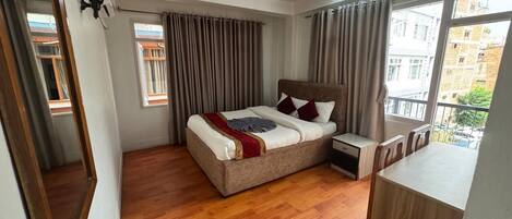 A bedroom with a bed, bedside table, and a view of the outside.