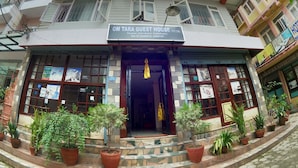 A multi-story building with a sign for "OM Tara Guest House Pvt. Ltd." at the entrance, featuring a staircase with potted plants and a view of the street. - Om Tara Guest House (Kathmandu)
