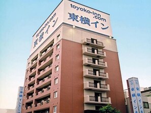 A multi-story building with a sign for 'toyoko-inn.com' and Japanese text.