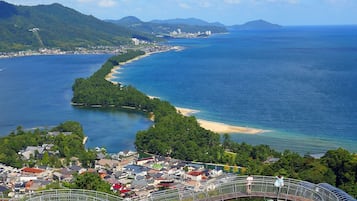Un pueblo costero con un puente, una playa y una montaña al fondo.