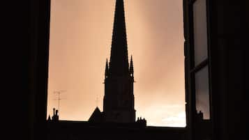 A silhouette of a tall, pointed building against a sunset sky, viewed through a window.
