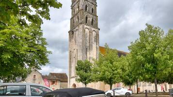 Ein roter Cabrio vor einer historischen Kirche mit einem hohen Kirchturm.