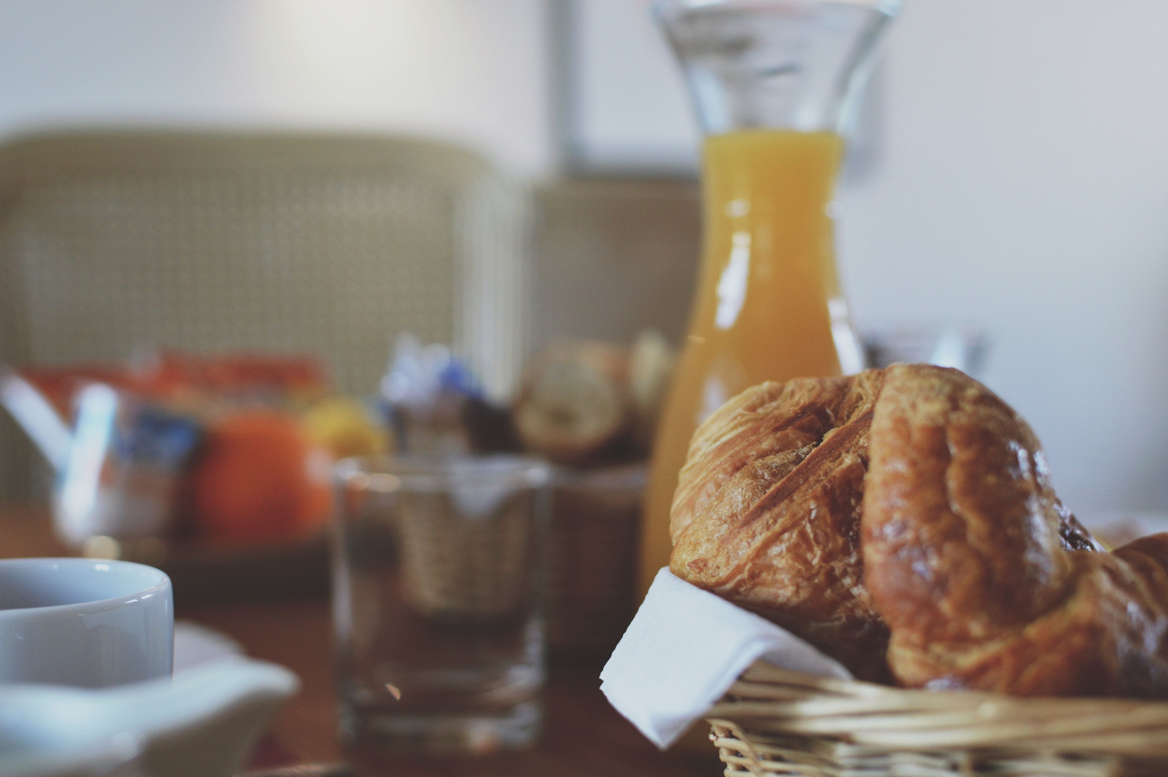 Uma mesa com croissants, um copo de sumo de laranja e uma chávena.