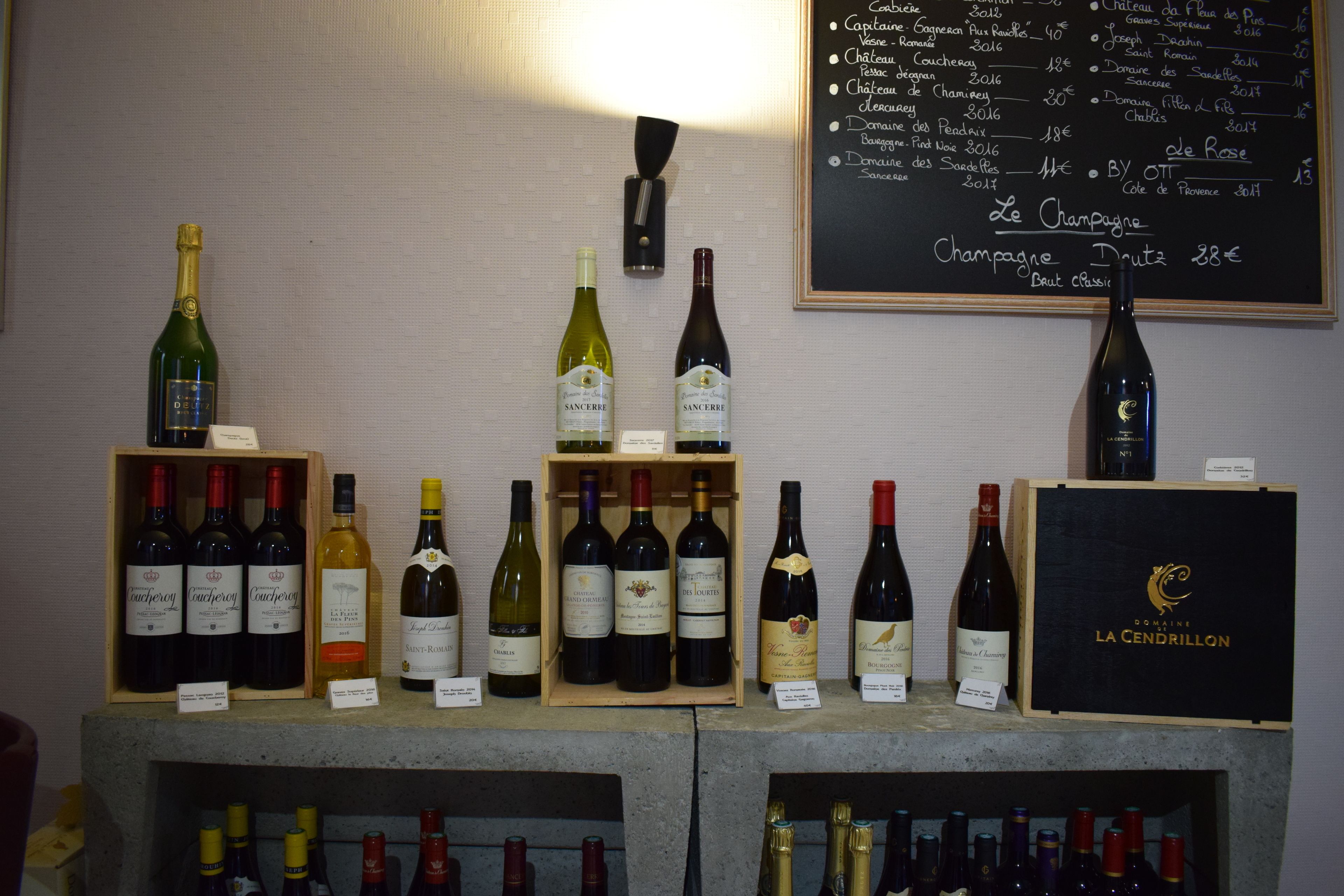 A wine display with various bottles and a chalkboard menu listing prices and wine names.