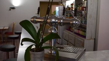 Zona de bar con una planta, un grifo y una estantería con botellas.