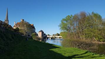 A riverside view with a stone bridge, historic buildings, and lush greenery.