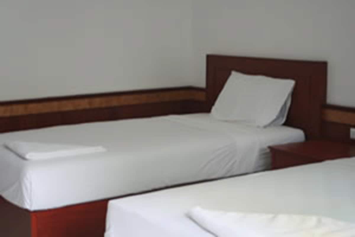 A single bed with a wooden headboard and white bedding in a hotel room.