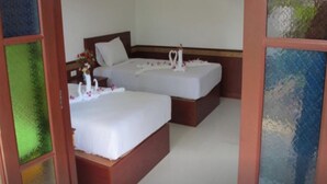 Habitación de hotel con dos camas individuales, cada una con cubrecama blanco y una decoración de cisnes.