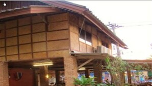 Un edificio tradicional de madera con techo de tejas, entrada de ladrillo y plantas en macetas.