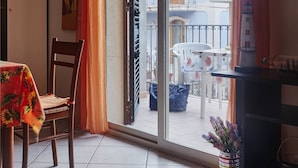 Un balcon avec une table et des chaises, un vase rempli de fleurs et une vue sur les bâtiments.