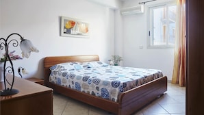 Une chambre avec un lit en bois, un tableau accroché au mur et une fenêtre avec des rideaux.