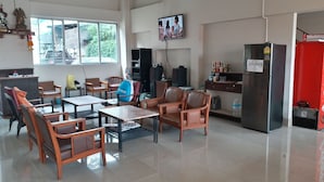 A spacious room with wooden furniture, a television mounted on the wall, and a refrigerator. - New Wanchai Hotel Pakchong (Pak Chong)