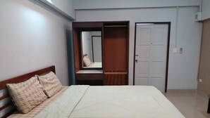 A bedroom with a bed, a wardrobe, and a door. - New Wanchai Hotel Pakchong (Pak Chong)