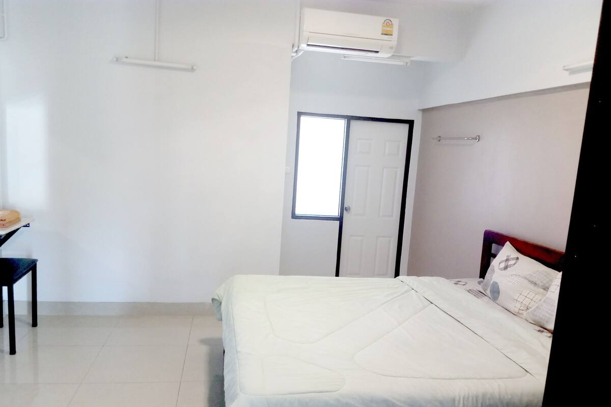 A bedroom with a bed, a desk, and a door.