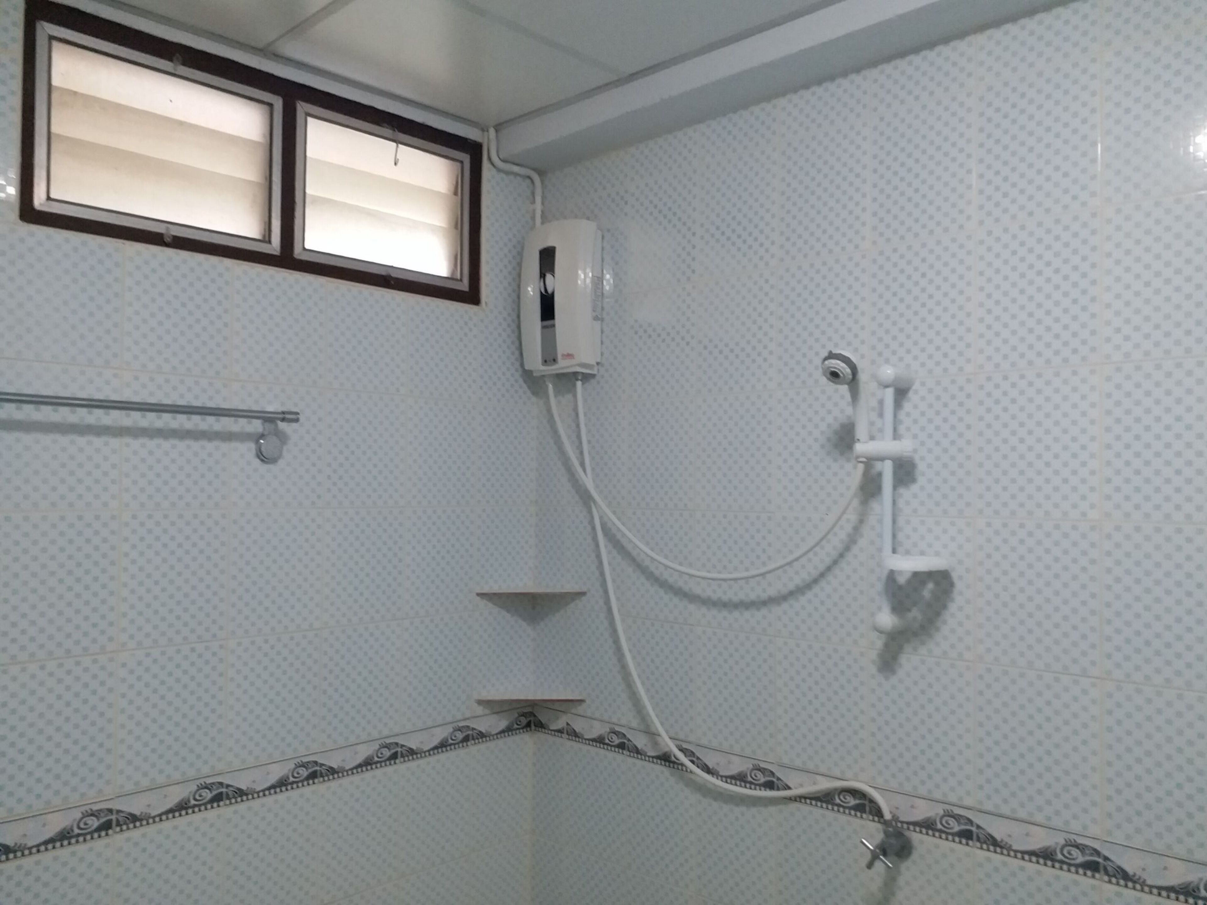 A bathroom with a shower, a towel rack, and a window with blinds.