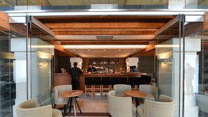 A modern bar area with a bartender, wooden ceiling, glass walls, and seating. - Hydrama Grand Hotel (Drama)