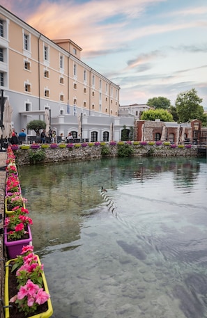 Un canal con jardineras florales, un muro de piedra y edificios al fondo.