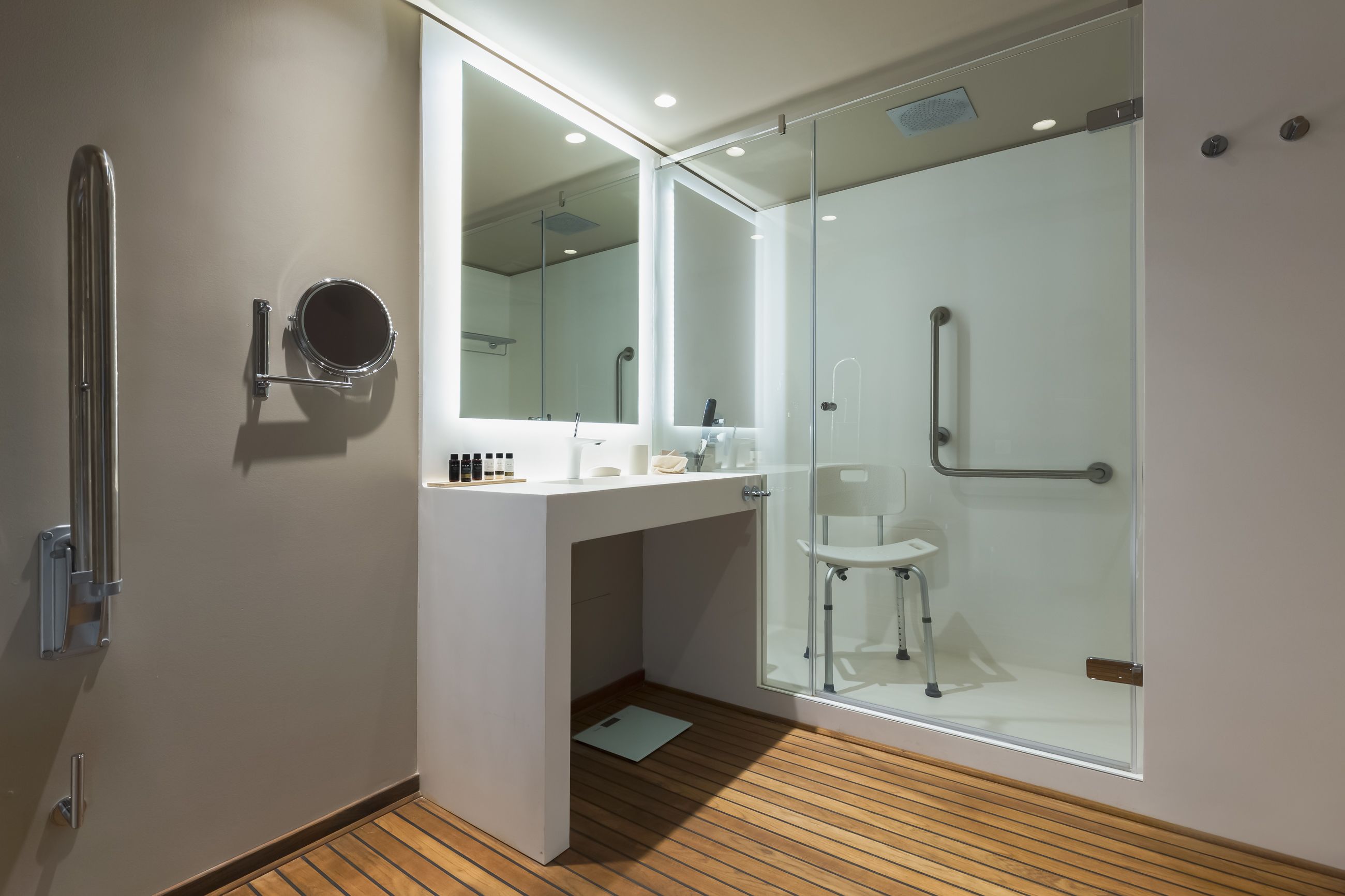 Un baño moderno con cabina de ducha de vidrio, un lavabo blanco y un espejo.