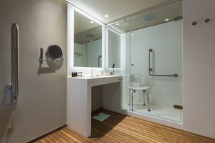 Un baño moderno con cabina de ducha de vidrio, un lavabo blanco y un espejo.