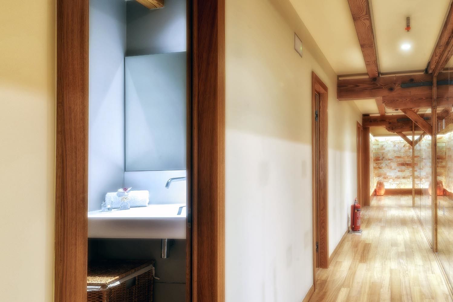 A hallway with wooden beams, a sink with a towel, and a wicker basket.