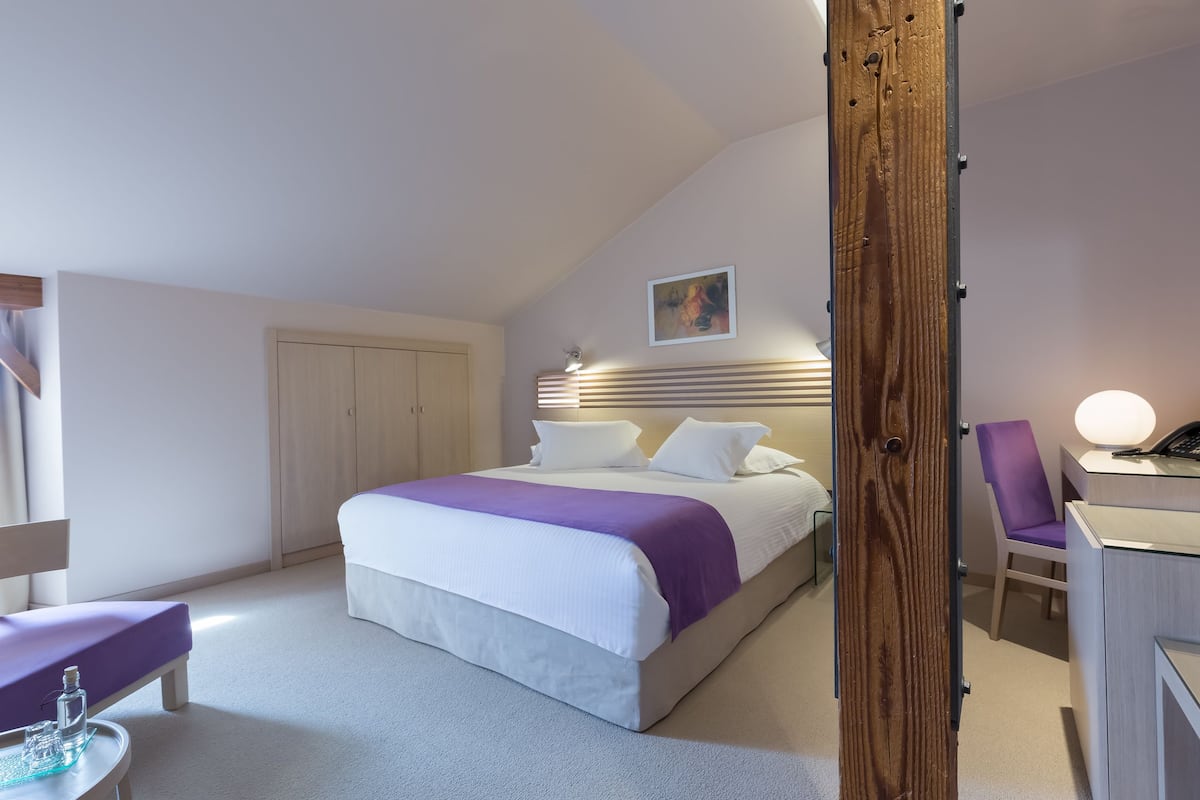 Ein Hotelzimmer mit Bett, Schreibtisch, Stuhl und Kleiderschrank.