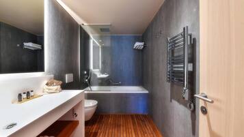 A modern bathroom with a wooden floor, a white sink with a mirror, a bathtub, and a towel rack.
