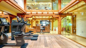 A gym with treadmills and exercise equipment, wooden beams, and a glass wall. - Hydrama Grand Hotel (Drama)