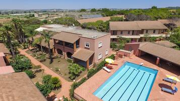 Relax by the large rectangular pool surrounded by a tiled deck and lush greenery.